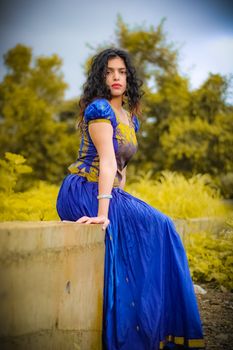 Stunning portrait of a woman in a vibrant blue dress posing outdoors on a sunlit day. 6138917
