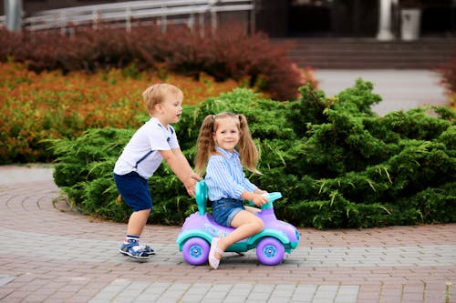 Boy Pushing a Girl Riding in Toy Car