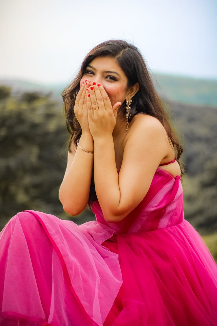 Woman In Pink Dress Hiding Smile With Hands