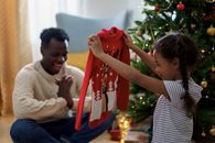 A Girl Smiling While Holding a Red Christmas Sweater