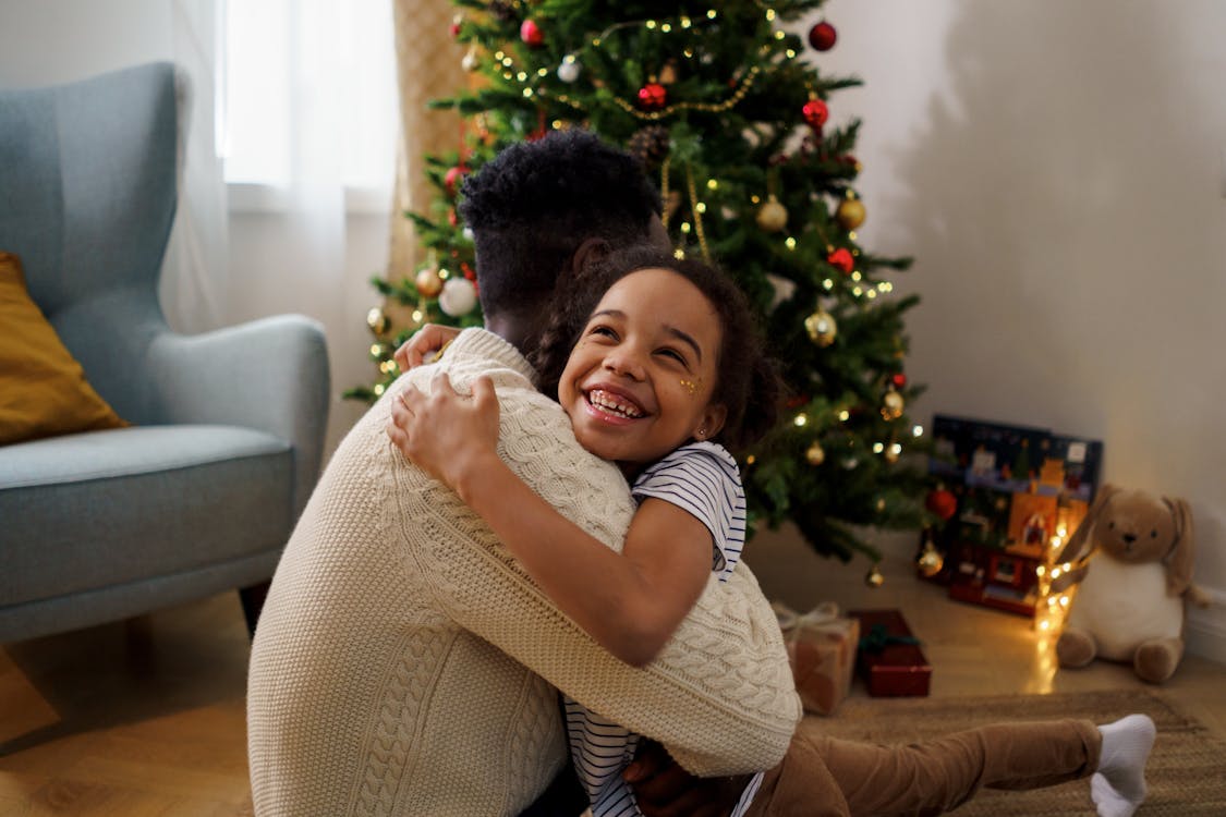 ¿Qué tipos de cestas hay? 3 Foto de homem recebendo abraço de filha pequena e sorridente em frente à árvore de Natal