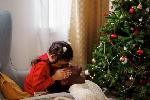 Free A warm moment of father and daughter bonding next to a Christmas tree indoors. Stock Photo