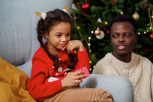 Free A father and daughter enjoying festive moments by a Christmas tree indoors. Stock Photo