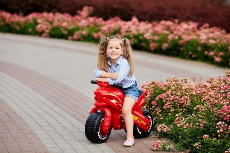 A Girl In Riding A Red Motorcycle Toy