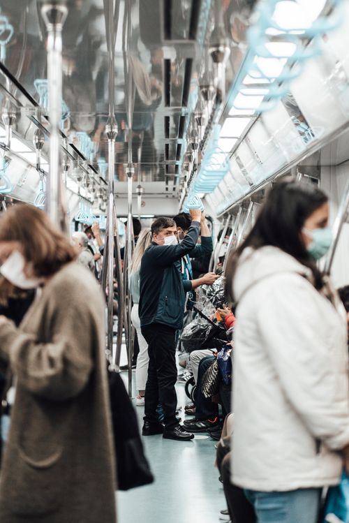Free Side view of anonymous people in warm casual clothes and protective masks riding modern subway train during COVID 19 Stock Photo