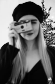 Blurry portrait of a woman in a beret holding a film camera, exuding vintage charm.