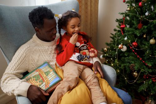 Free Dad and daughter enjoying Christmas together by the decorated tree. Stock Photo