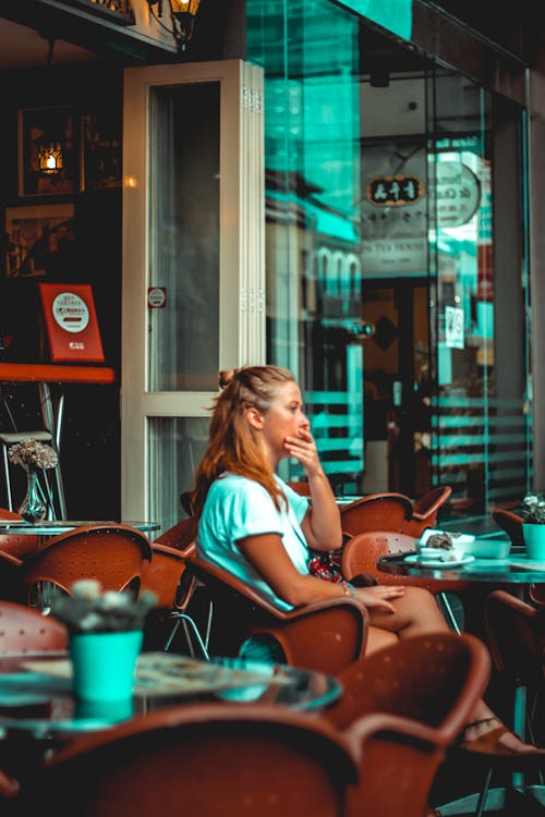 Woman in White Tank Top Sitting on Brown Chair