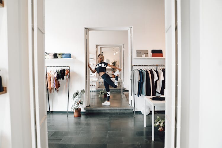 Fit Sportswoman Stretching Leg In Clothes Shop