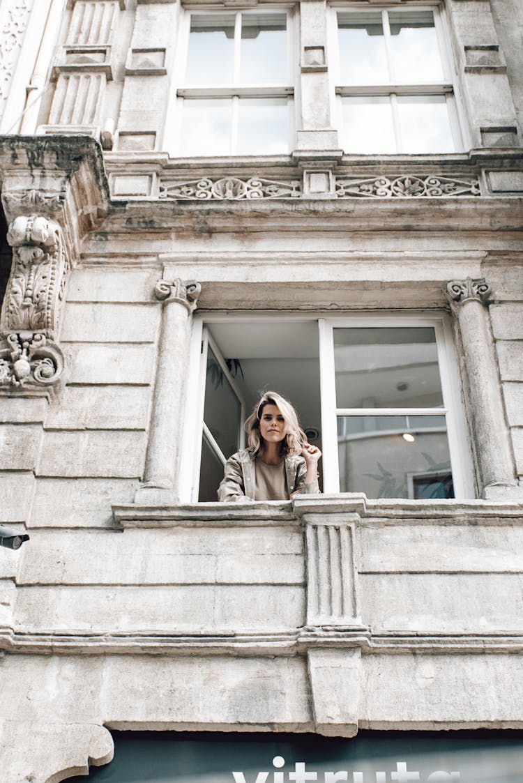 Woman Looking Out Of Window Of Old Stone House