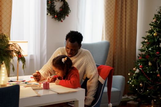Father and daughter engaged in creative crafts during Christmas at home.