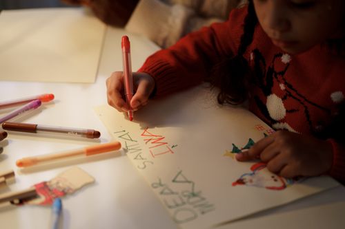 Free A young girl writes a letter to Santa using colorful markers during the Christmas season. Stock Photo