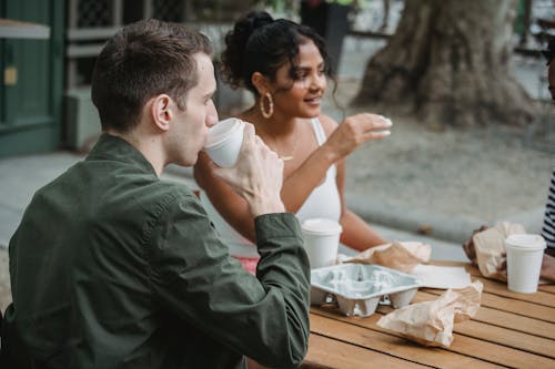 Free Multiracial millennials resting in cafe with takeaway coffee and pastries Stock Photo