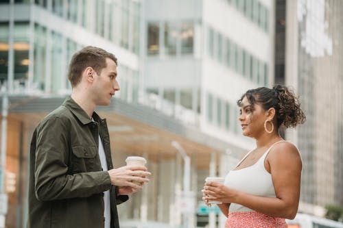 Free Young diverse coworkers having coffee break together on city street Stock Photo