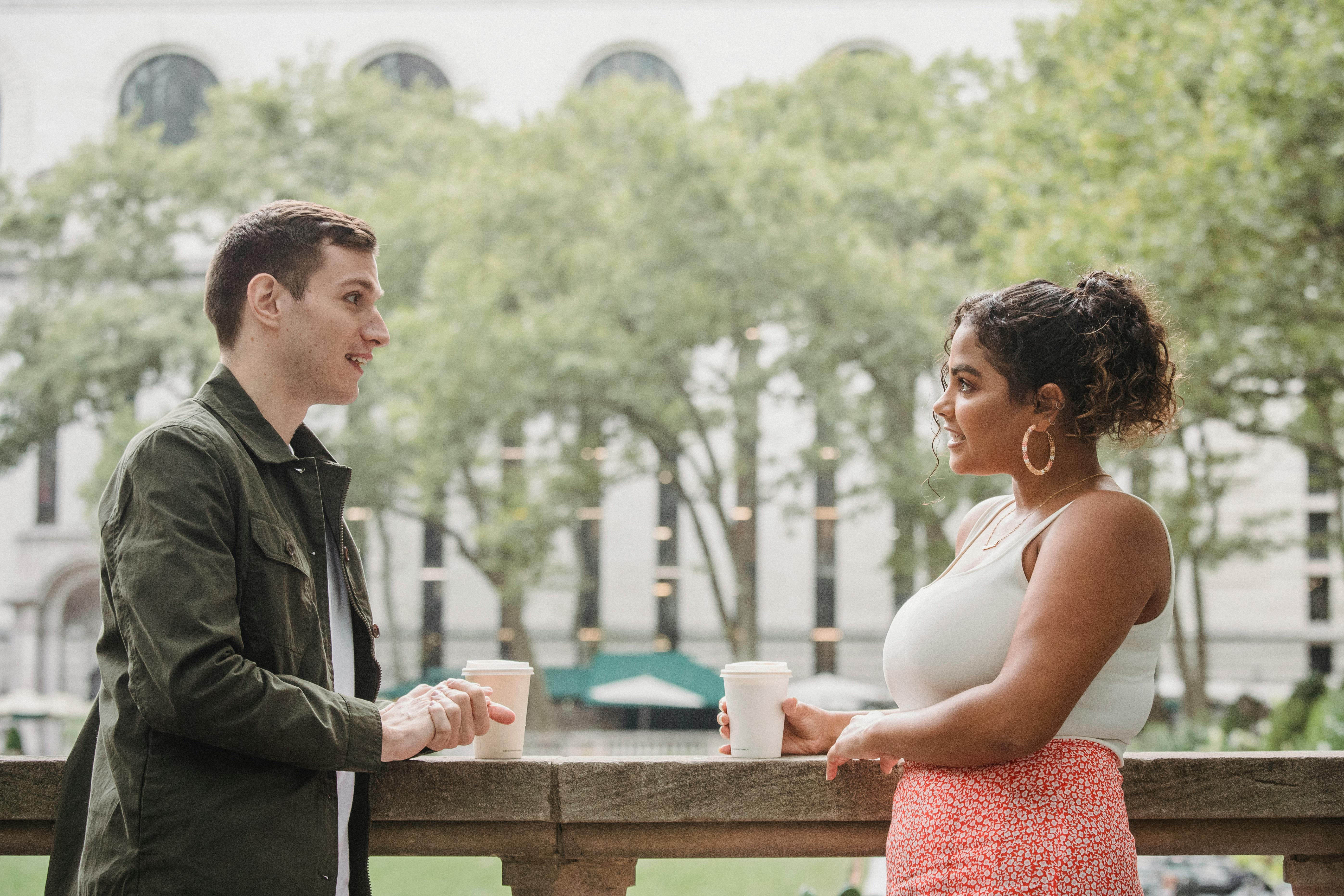 young diverse students drinking coffee to go in campus park