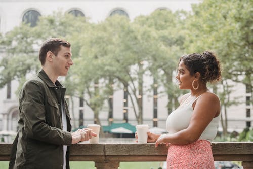 Free Young diverse students drinking coffee to go in campus park Stock Photo