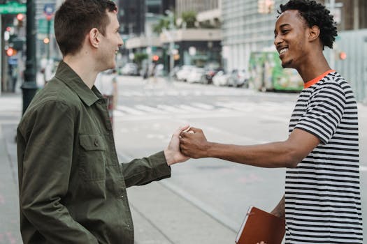Two young adults greet each other warmly on a city street, showcasing friendship and connection.