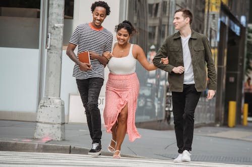 Free Happy diverse friends smiling while walking on zebra crossing Stock Photo