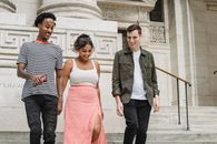 Positive multiethnic friends walking downstairs near building