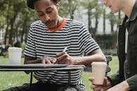 Crop multiracial men studying on street