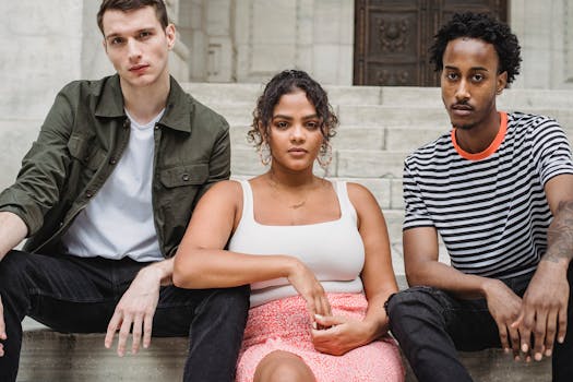 Diverse group of friends sitting on city steps, showcasing modern casual fashion.