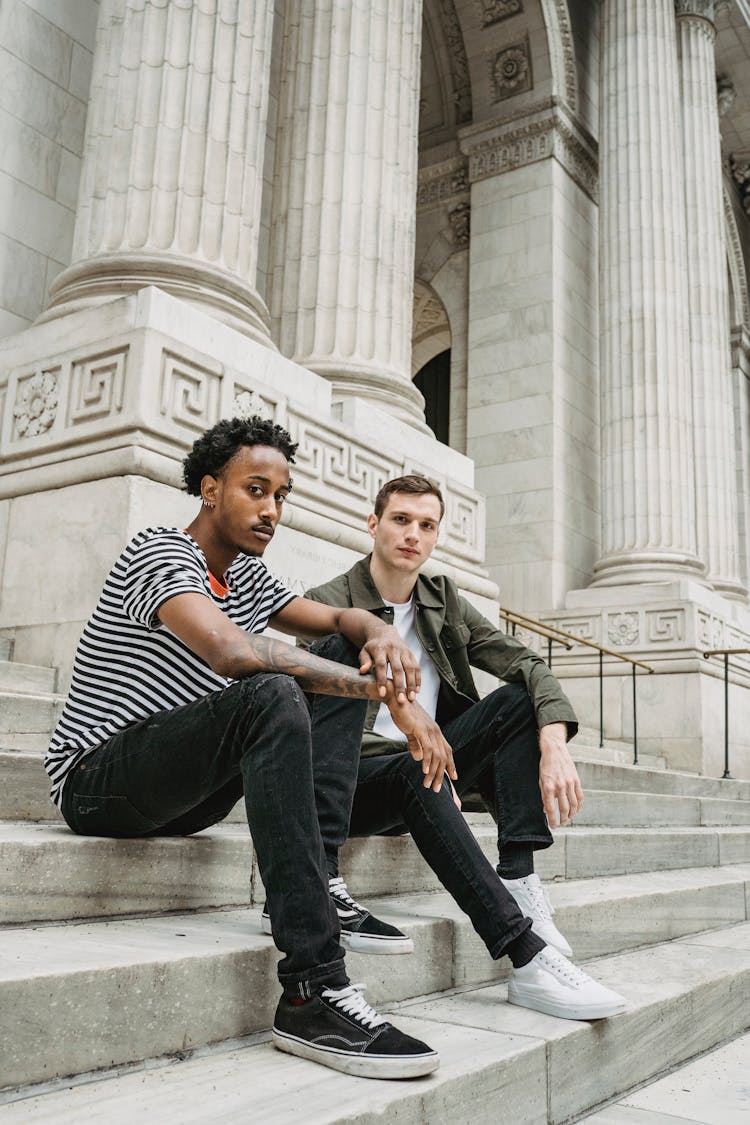 Stylish Young Multiracial Male Friends Resting On Old Building Stairs