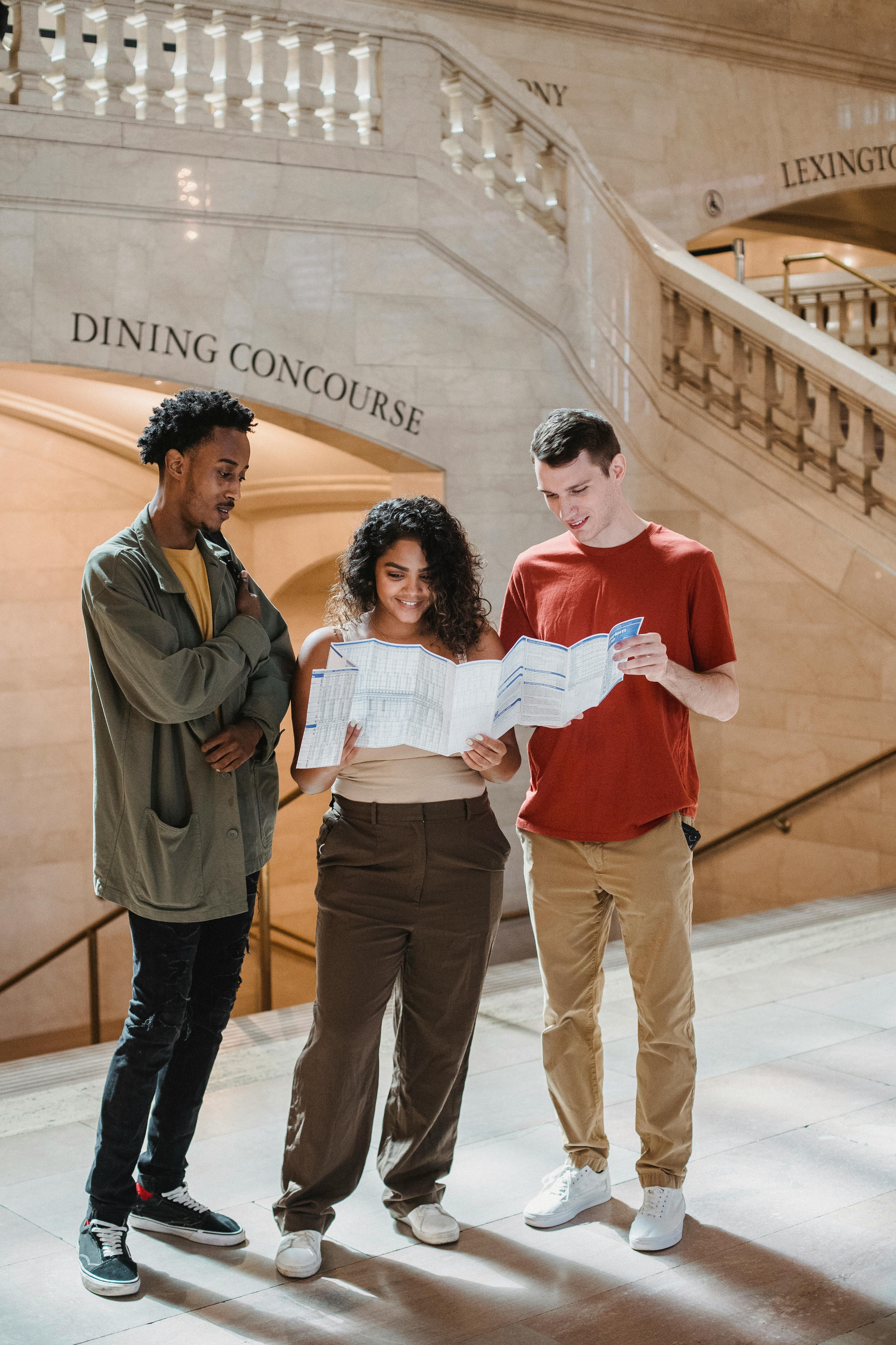 happy diverse tourists exploring map in railway station