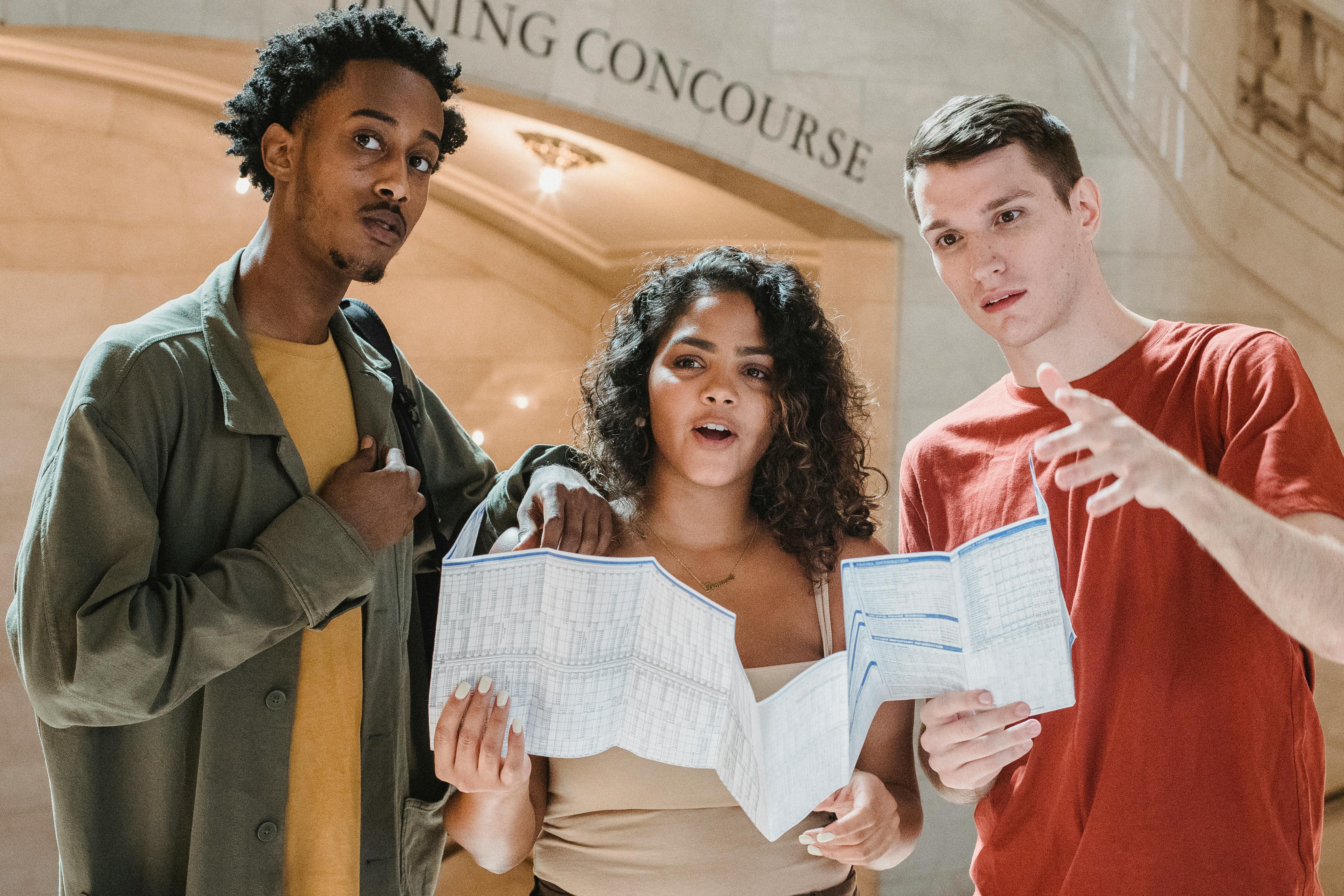 astonished young diverse tourists reading map