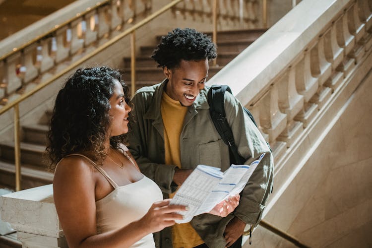 Happy Multiracial Couple Smiling While Exploring Map In Building