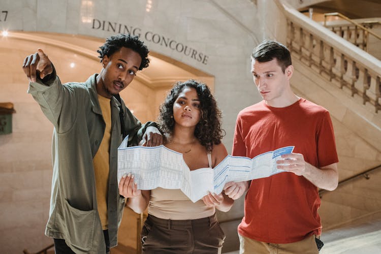 Concentrated Young Multiethnic Friends With Map In Railway Station