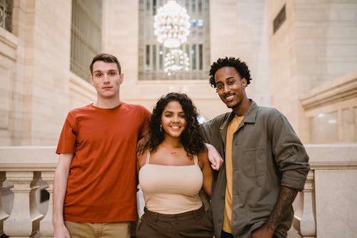 Happy multiethnic friends embracing in light hall with ornamental walls