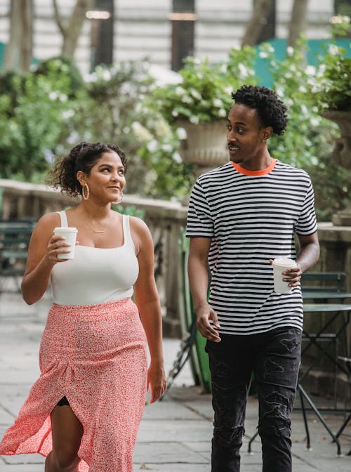 Free Positive multiracial couple walking with takeaway coffee Stock Photo