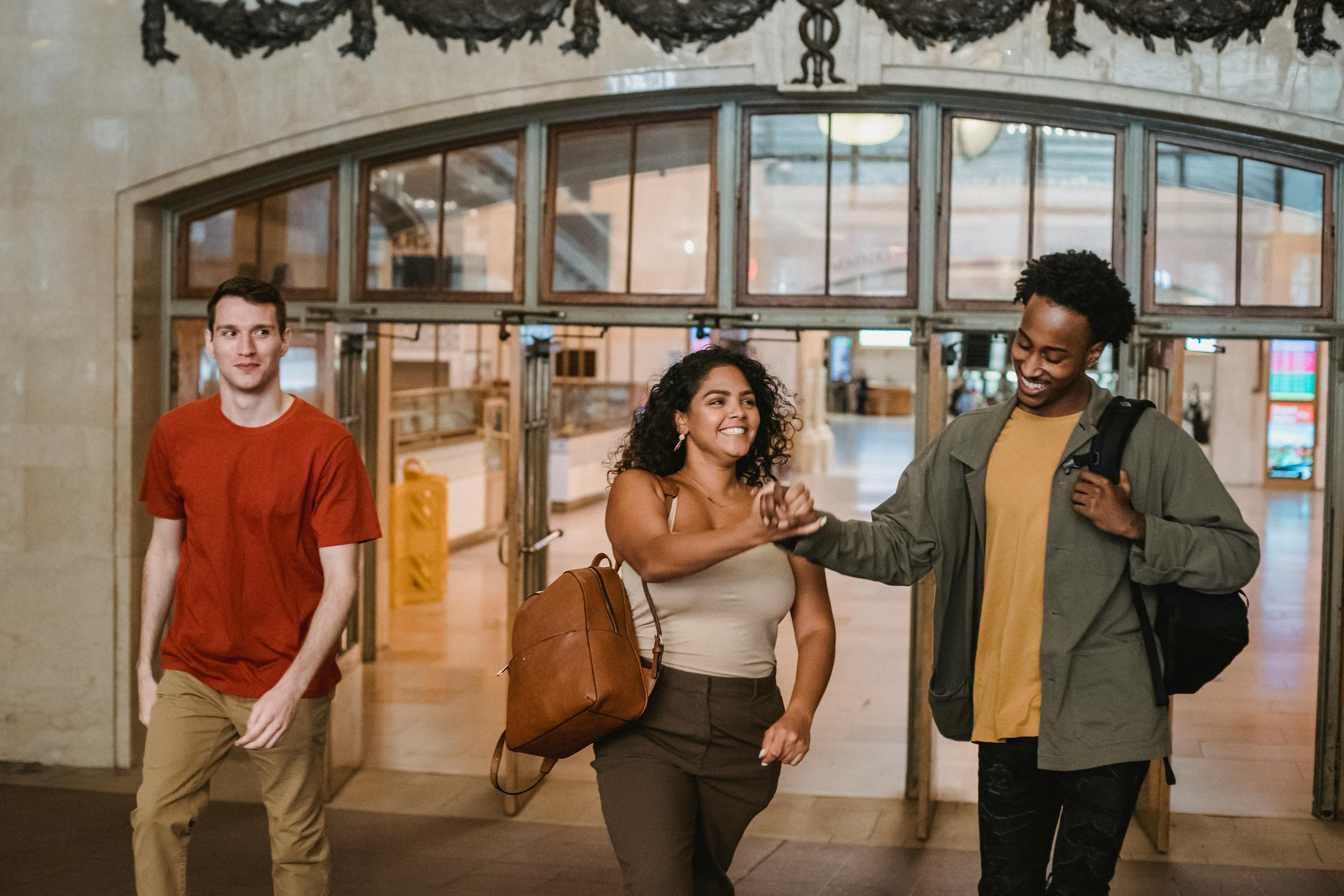 smiling multiethnic friends walking through open doors in university