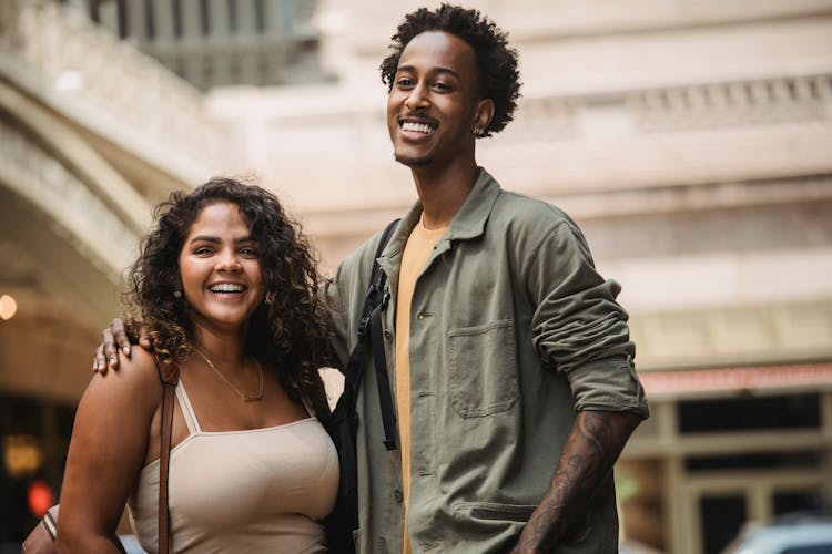 Laughing Young Diverse Couple Standing On Blurred Urban Background