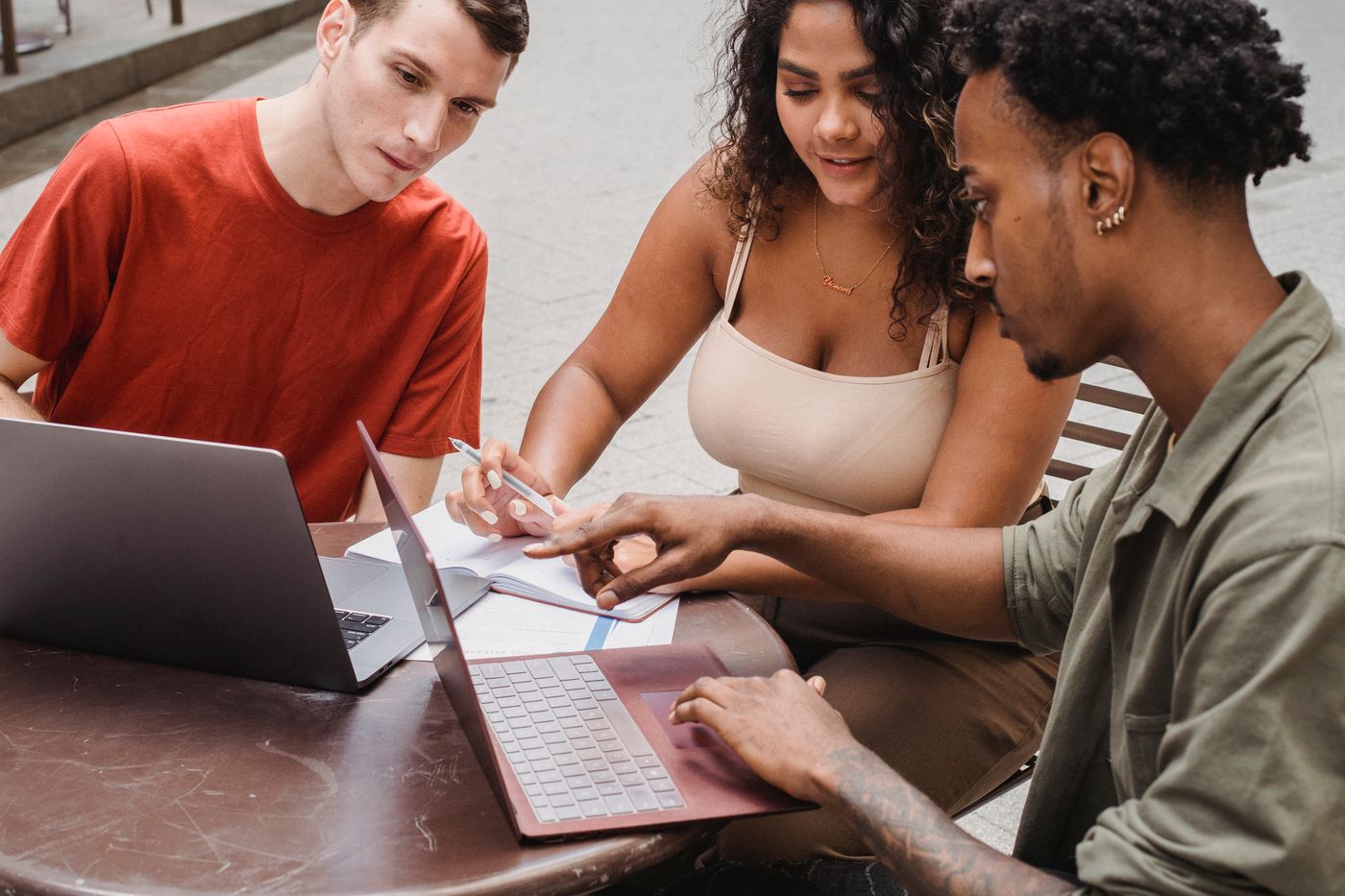 Diverse young adults collaborating around a laptop in a modern study space