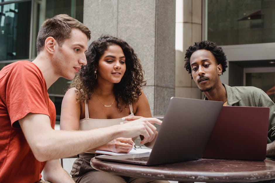 Group of diverse young male and female diverse colleagues discussing project details while working t