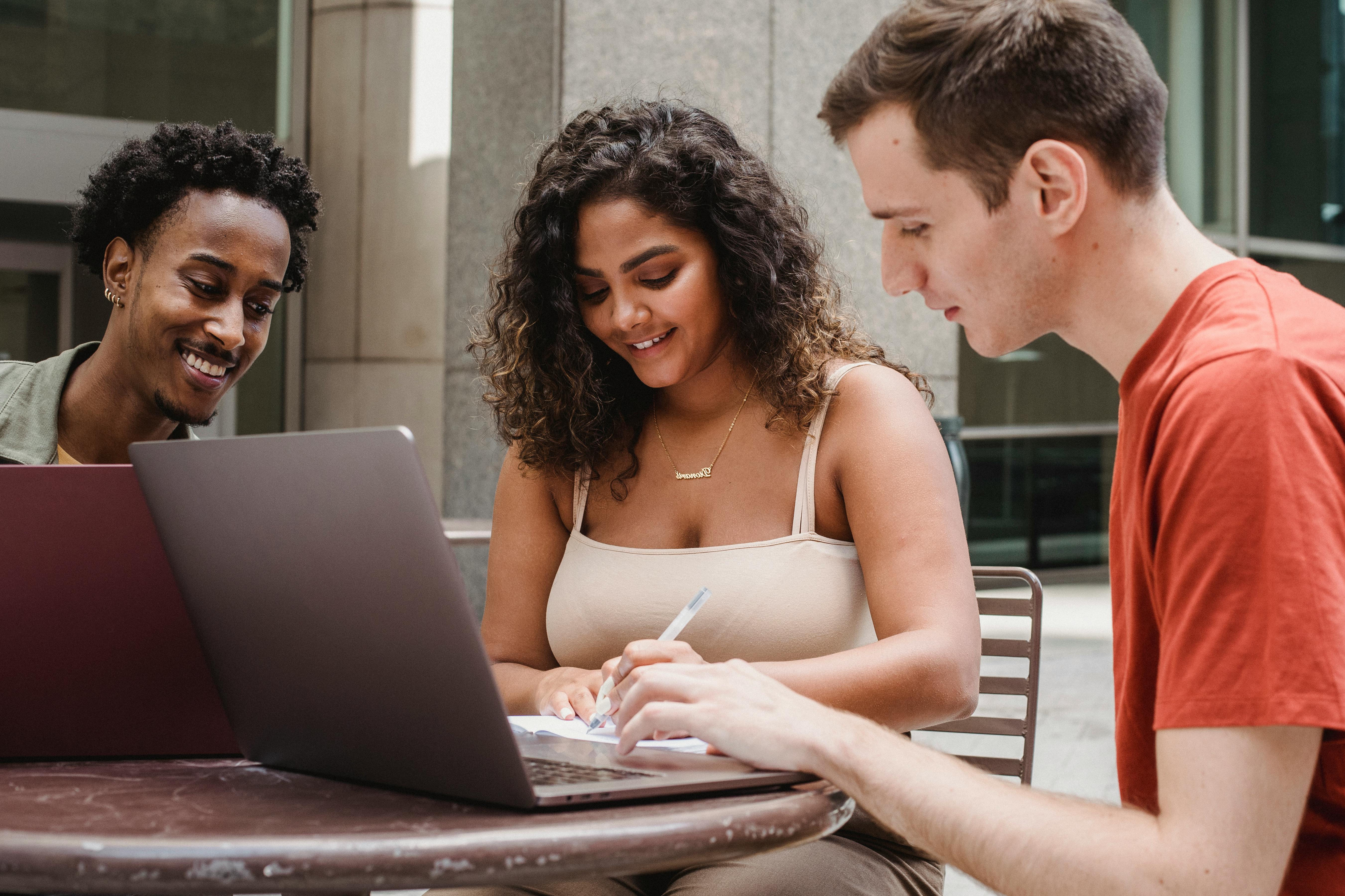 happy hispanic lady black man and male student doing homework together