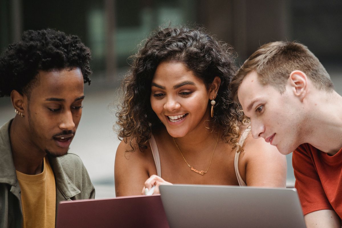 Mixed group of students collaborating on laptops together