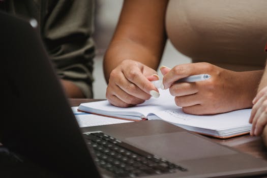 Close-up of colleagues collaborating and taking notes in an office setting.