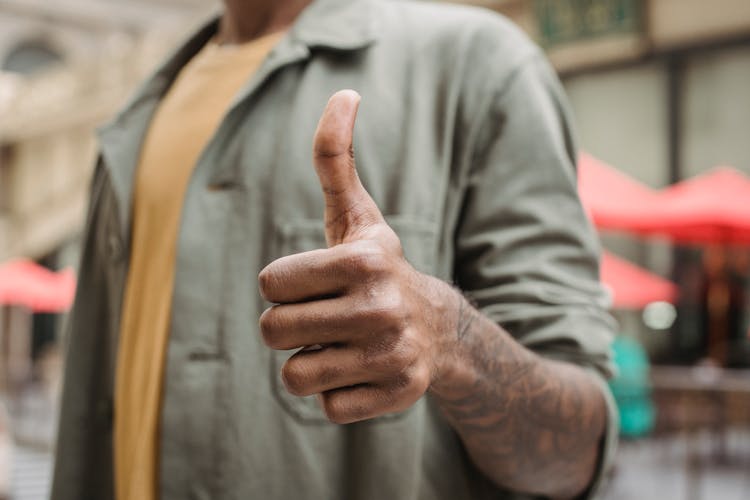 Anonymous Ethnic Man Demonstrating Thumb Up Sign On Street