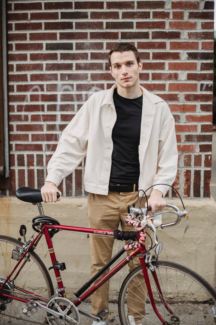 Serious Young Male Millennial With Bike Standing On City Street