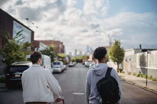 Unrecognizable male teens strolling on street in suburb area