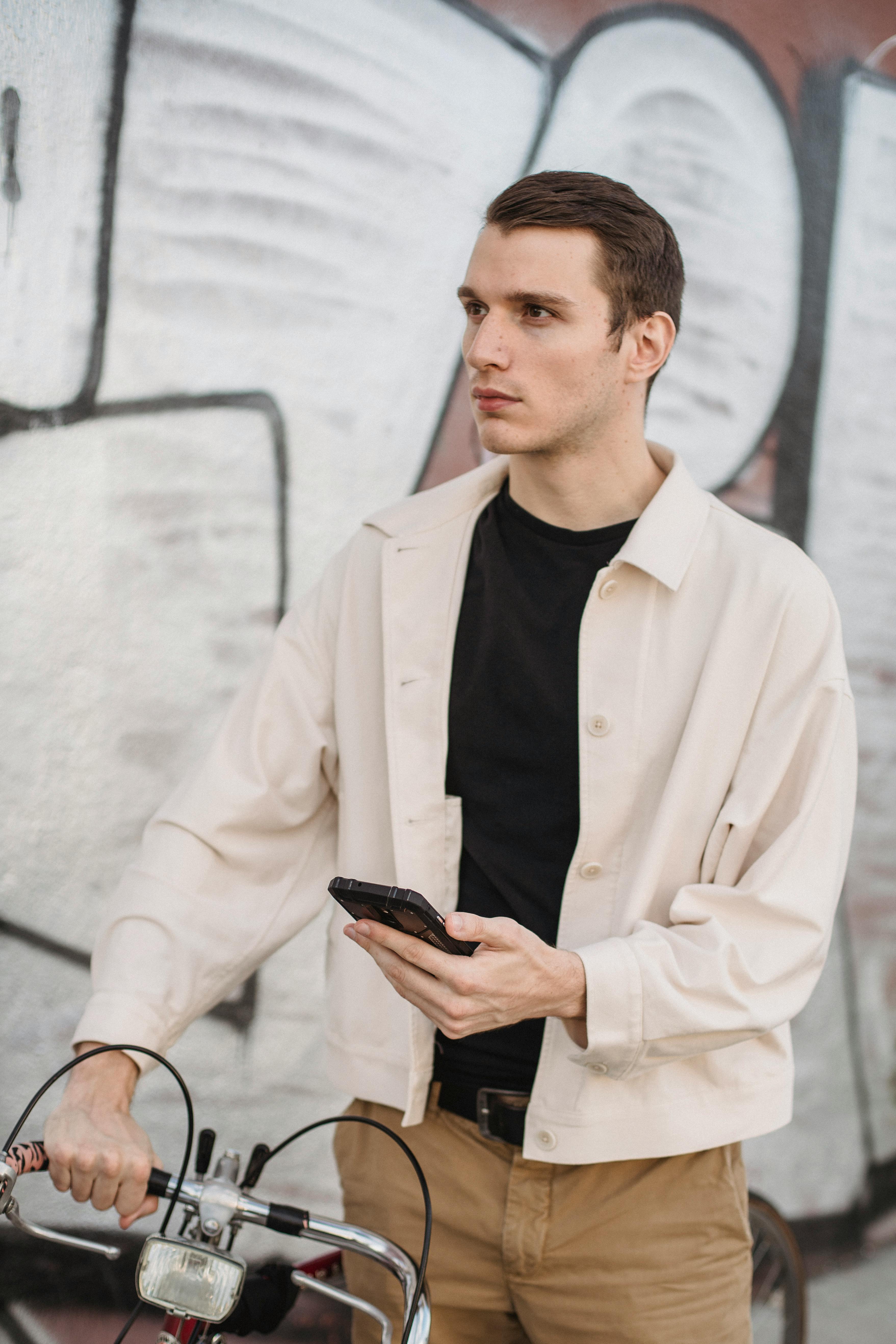 serious young man using smartphone near graffiti wall