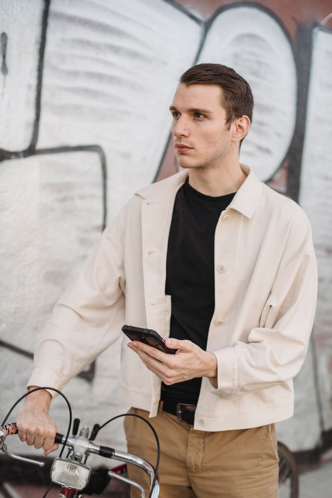 Cyclist standing beside a bicycle while reviewing information on a smartphone