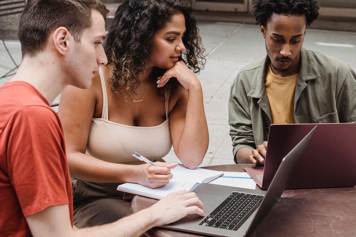 Trois apprenants adultes en apprentissage collaboratif travaillant ensemble sur une même tâche