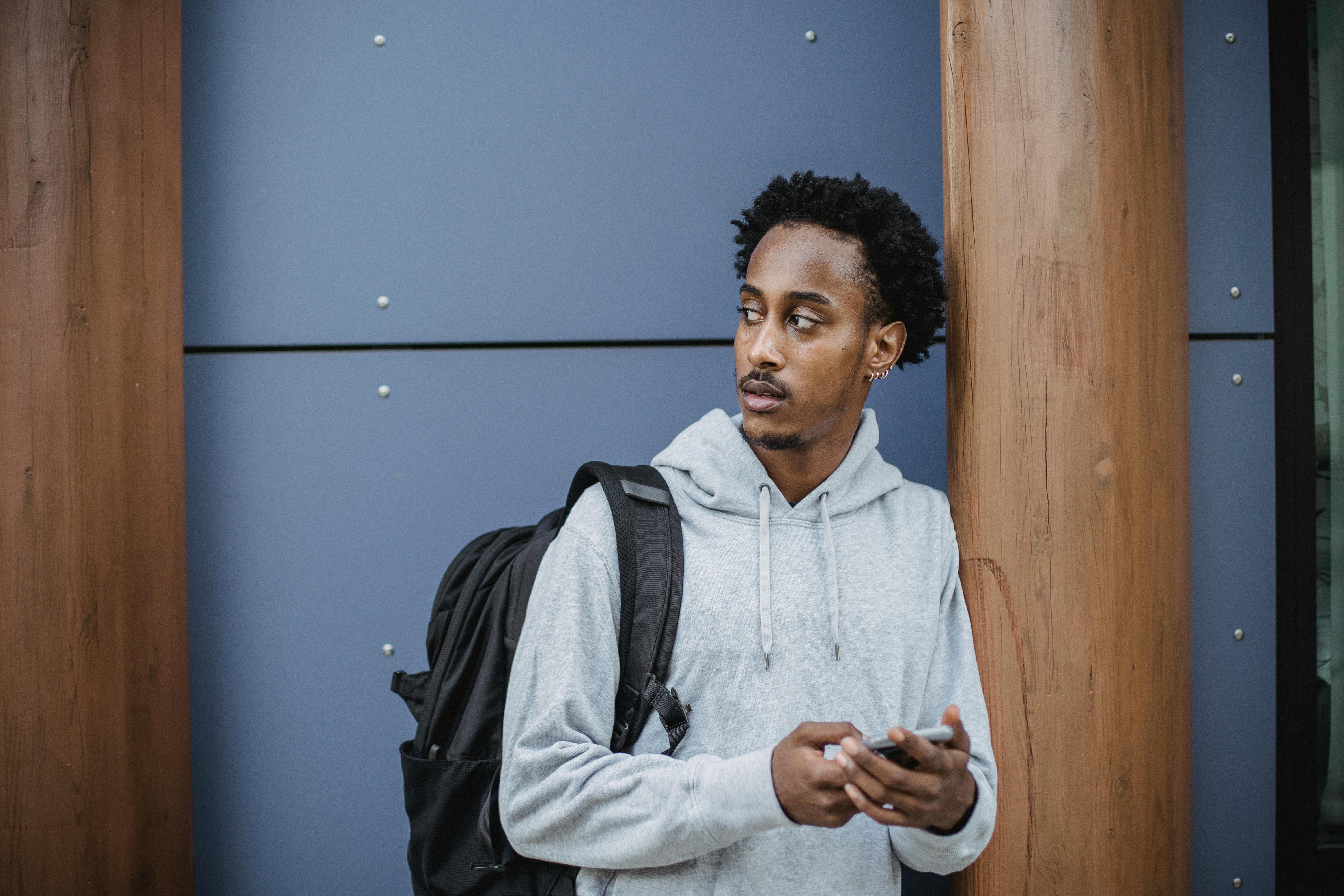 serious young black man browsing smartphone on street