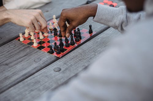 Unrecognizable multiracial men playing chess at lumber table