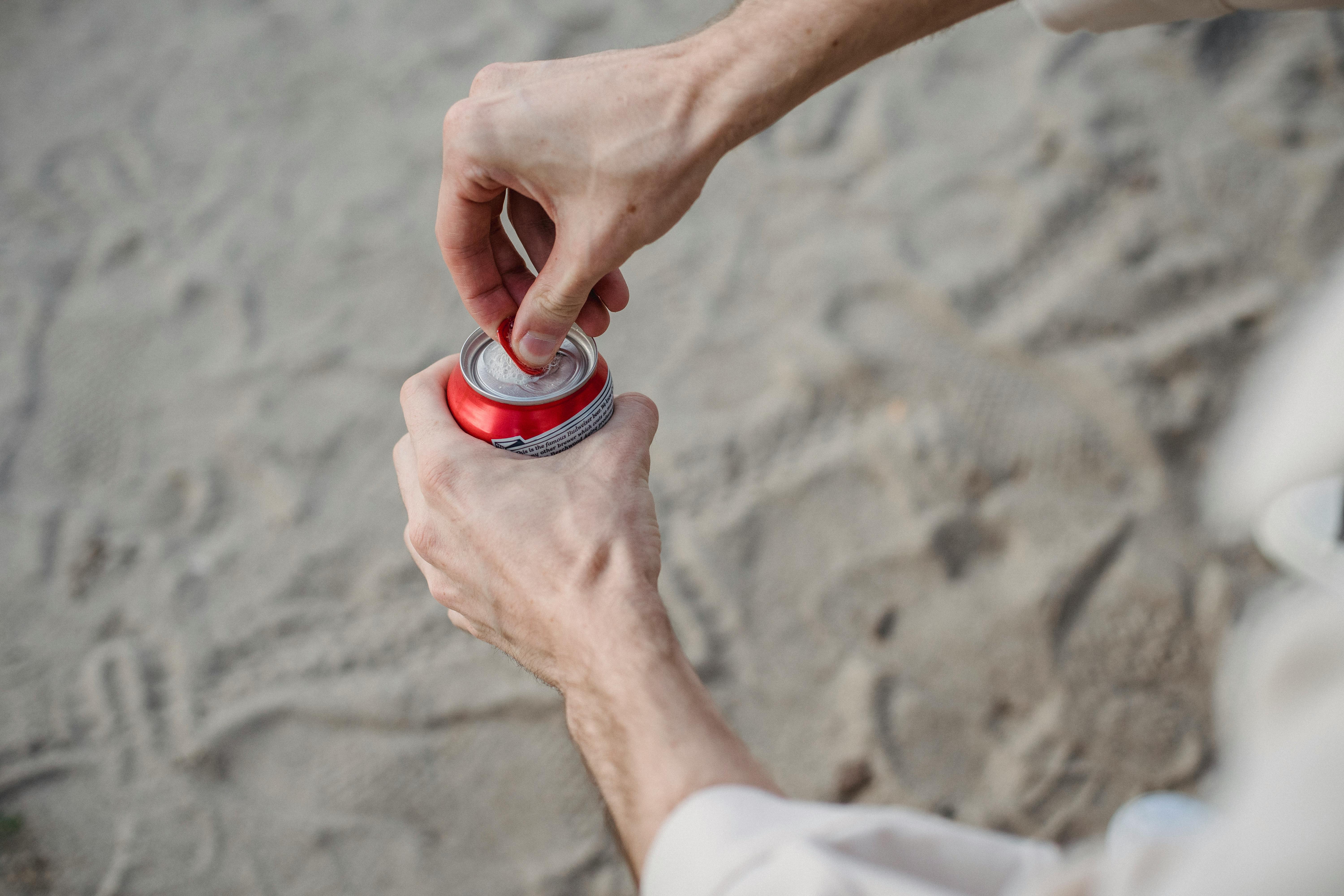 man opening can of drink in nature