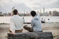 Diverse friends sitting on log on embankment