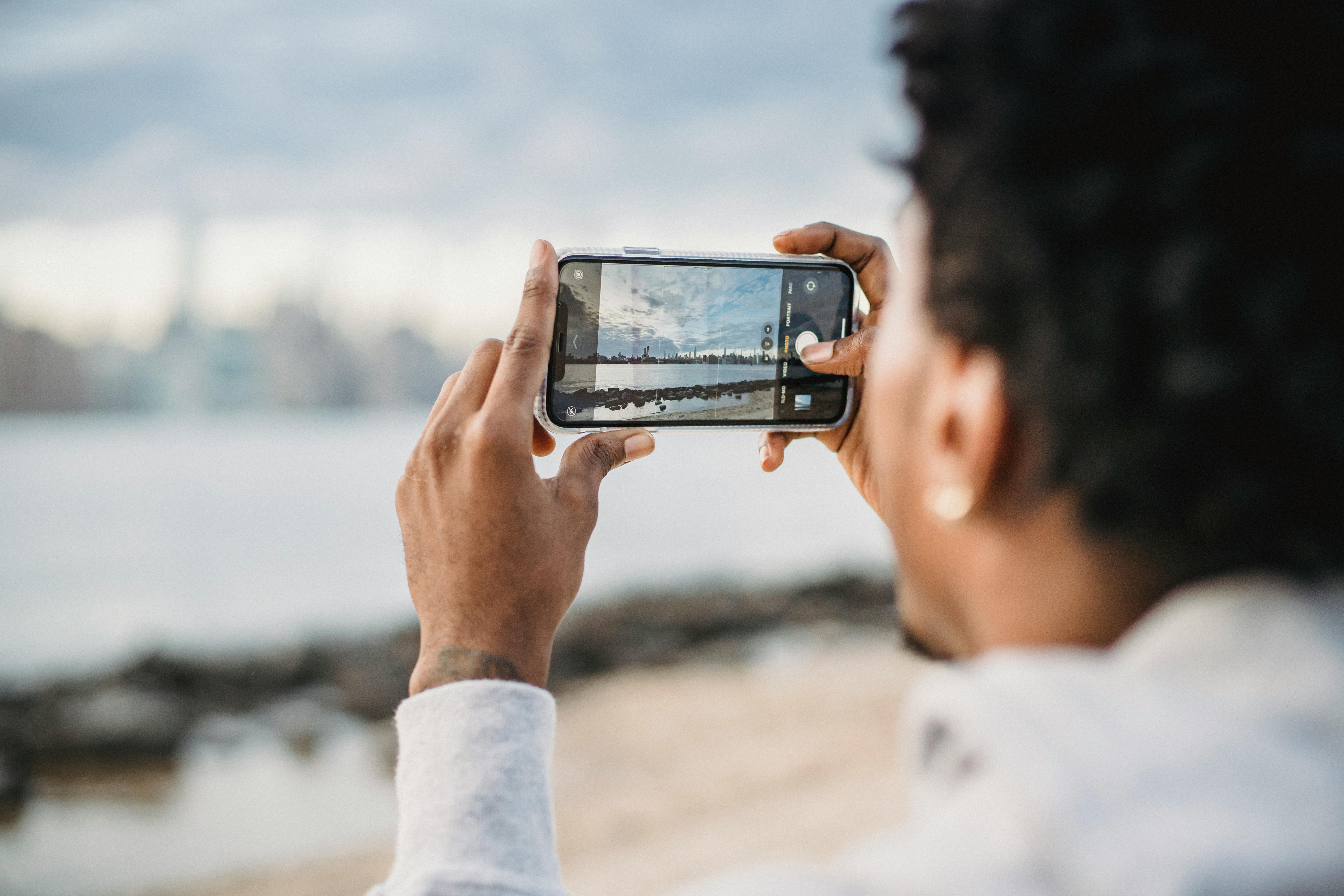 black woman taking photo of city on smartphone